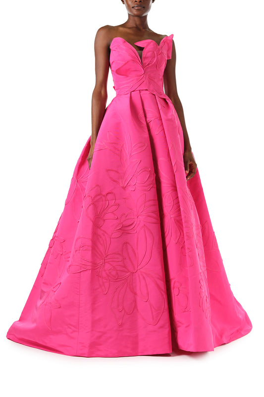 Monique Lhuillier Fall 2024 strapless, a-line ballgown in fuchsia floral embossed faille with draped asymmetrical bodice and full pleated skirt - front.