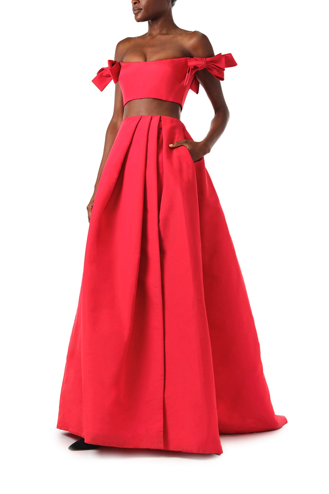 Monique Lhuillier Fall 2024 scarlet red faille pleated ballgown skirt with high front slit and pockets - front with hand in pocket.