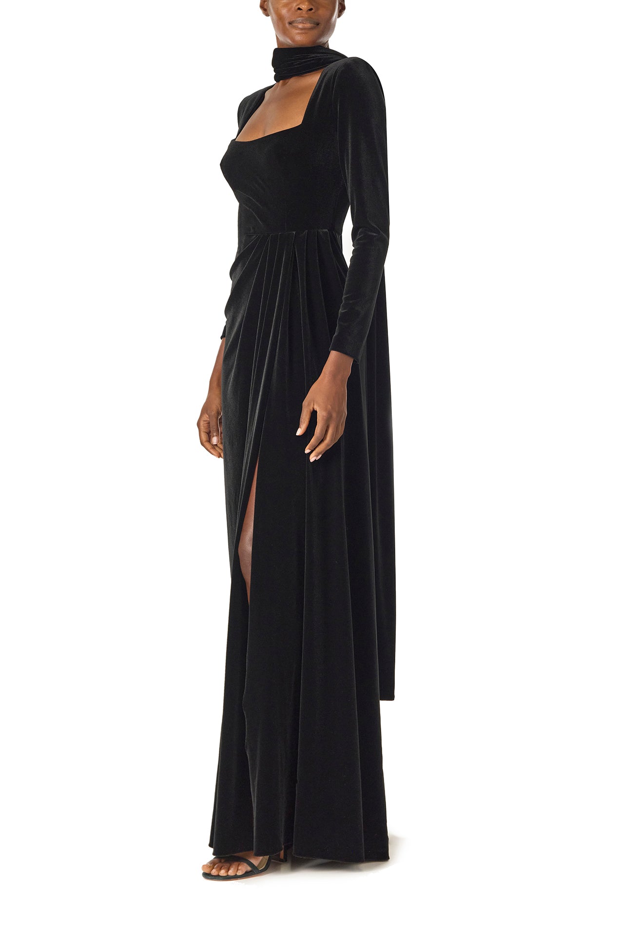 Monique Lhuillier Fall 2024 long sleeve gown with square neckline, front skirt draping and detached neck scarf in noir stretch velour - left with slit.