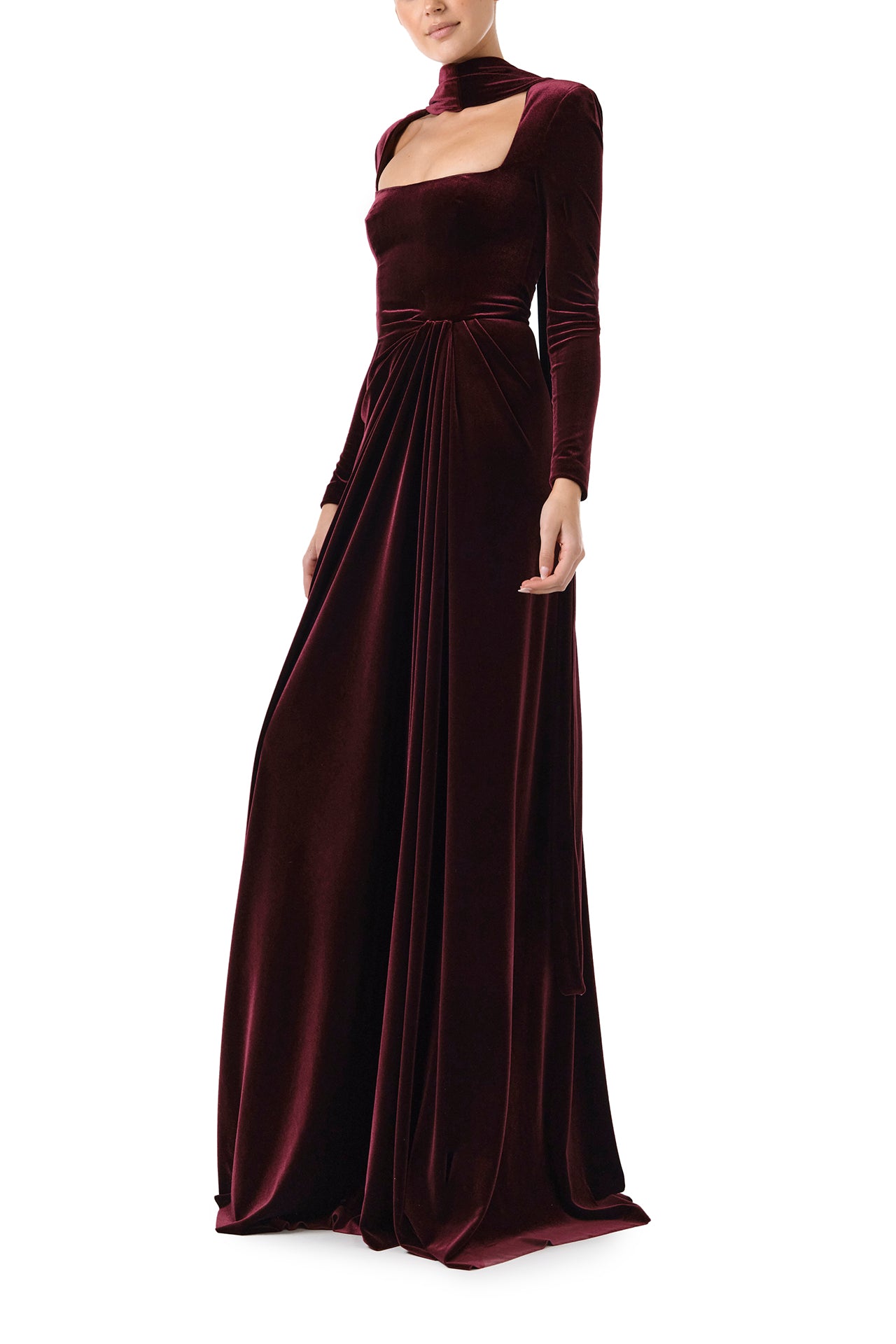 Monique Lhuillier Fall 2024 Long sleeve gown with square neckline, front skirt draping and detached neck scarf in Merlot colored stretch velour - left side.