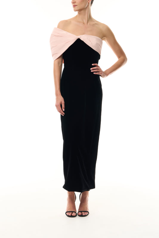 Monique Lhuillier Fall 2024 black velvet sheath dress with pale blush off the shoulder drapeda symmetric twist detail at neckline - front.