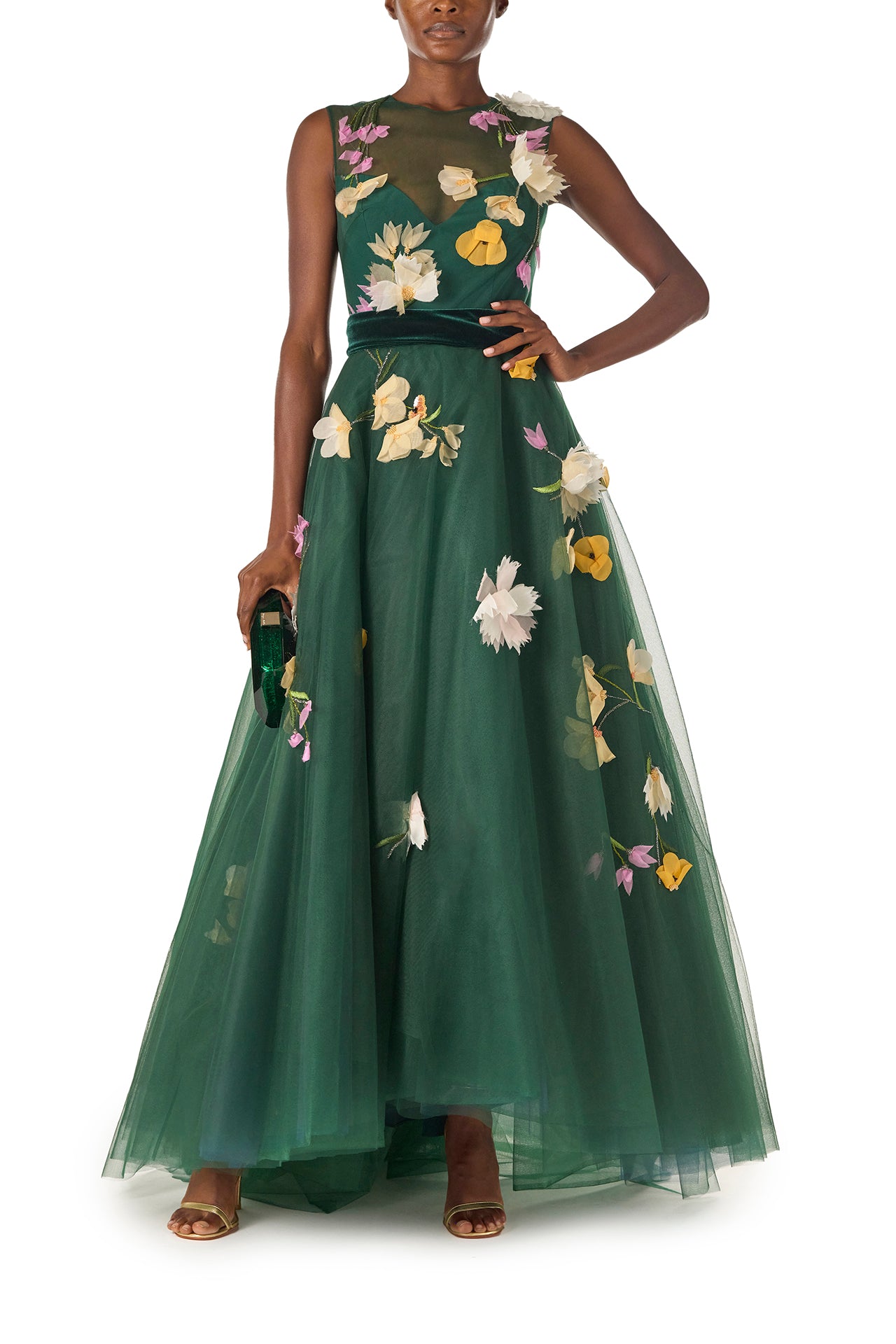 Monique Lhuillier Fall 2024 sleeveless, green tulle gown with floral embroidery, illusion neckline, full A-line skirt and velvet cummerbund at waist - front with Dasha emerald handbag.