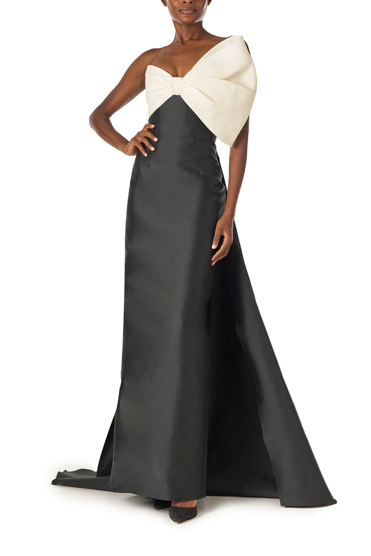 Monique Lhuillier Spring 2025 Strapless column gown with asymmetric draped bow neckline and pleated back train in Noir + Silk White Mikado - front.