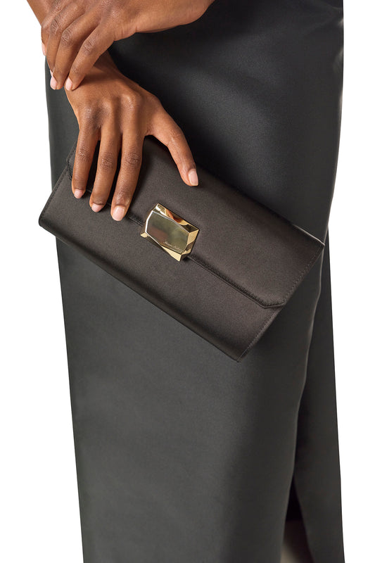 Satin evening envelope clutch with snap closure and gold optional strap in Noir- on model in black gown.