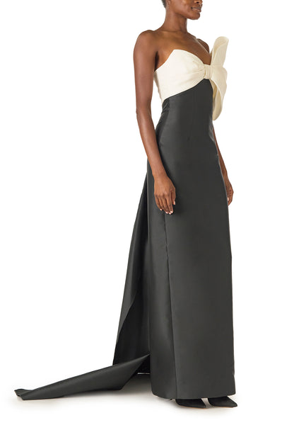 Monique Lhuillier Spring 2025 Strapless column gown with asymmetric draped bow neckline and pleated back train in Noir + Silk White Mikado - right side.
