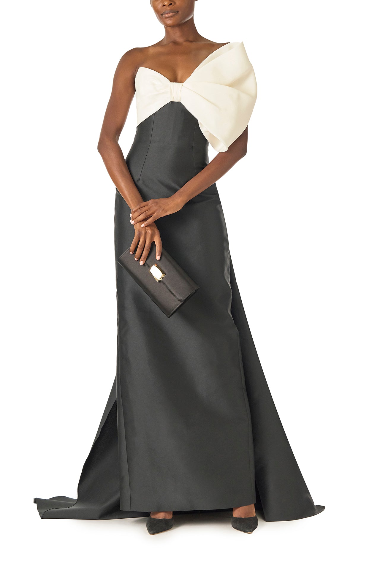 Monique Lhuillier Spring 2025 Strapless column gown with asymmetric draped bow neckline and pleated back train in Noir + Silk White Mikado - front with Delphine clutch.