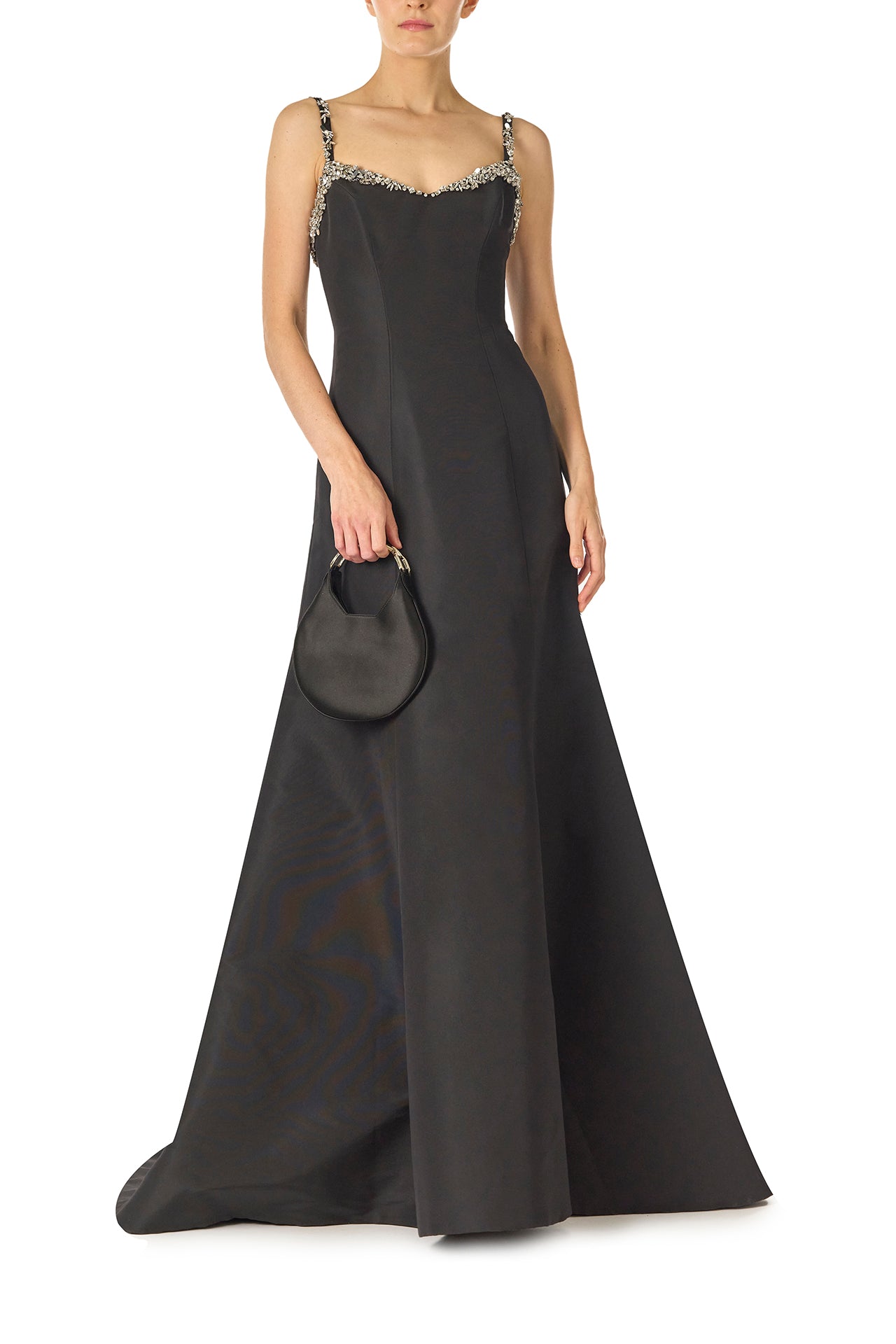 Monique Lhuillier Spring 2025 Modified trumpet gown with crystal beaded neckline and spaghetti straps in Noir Silk Faille - front with Demi handbag.