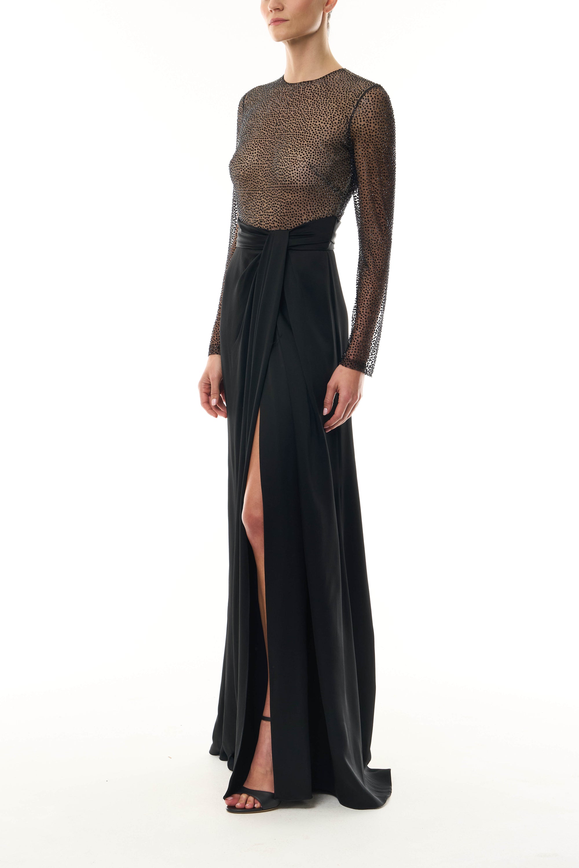 Monique Lhuillier Fall 2025 RTW Noir Long Sleeve Hotfix gown with embellished bodice and front slit - side.