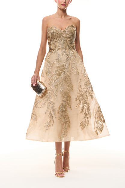 Monique Lhuillier Fall 2025 strapless dress with tea-length skirt and sweetheart neckline in gold feather embroidery -  front with gold Dasha Minaudière.