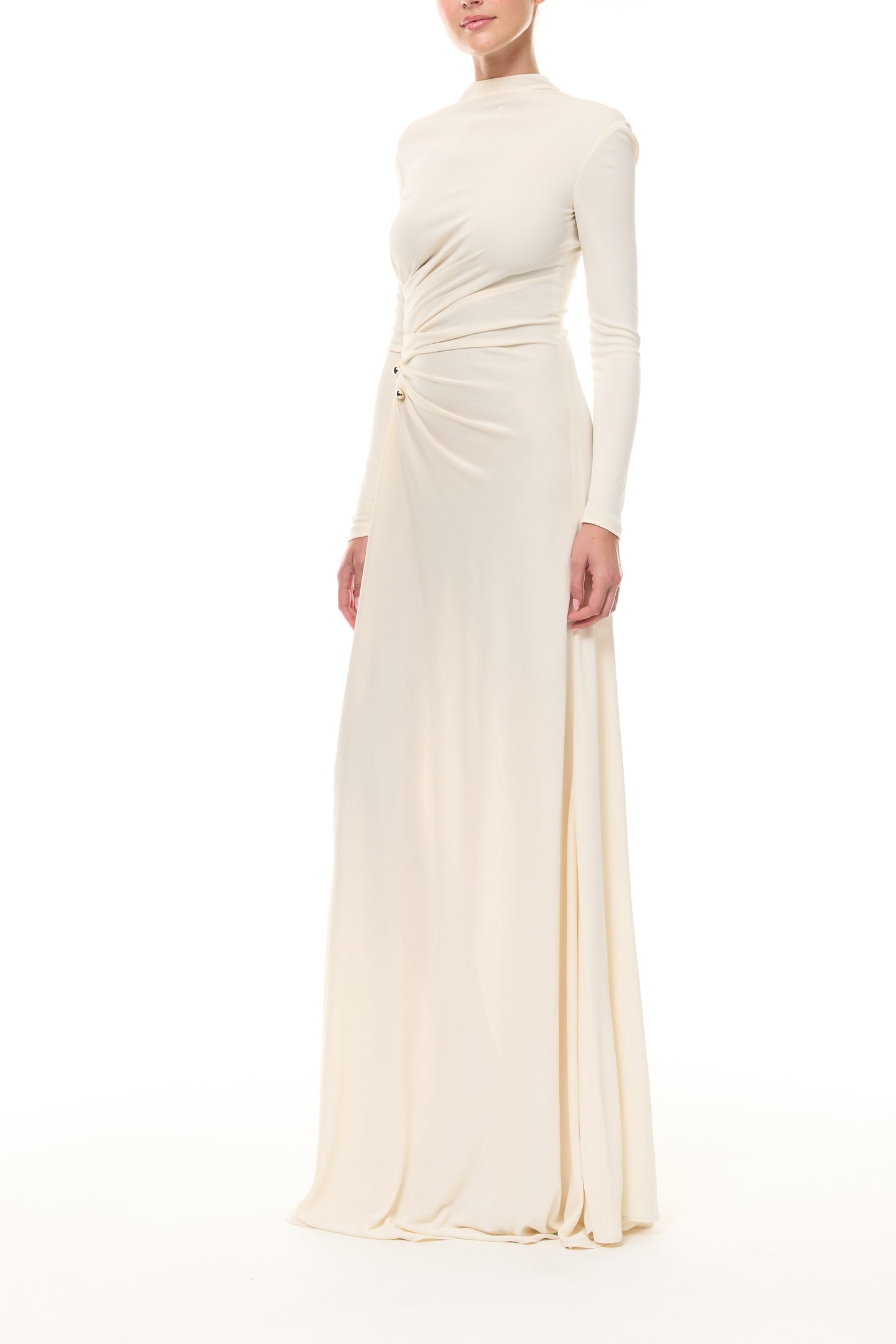 Monique Lhuillier Spring 2026 Ivory crepe jersey high neck long sleeved draped gown with slit and gold ball piercing - side. 