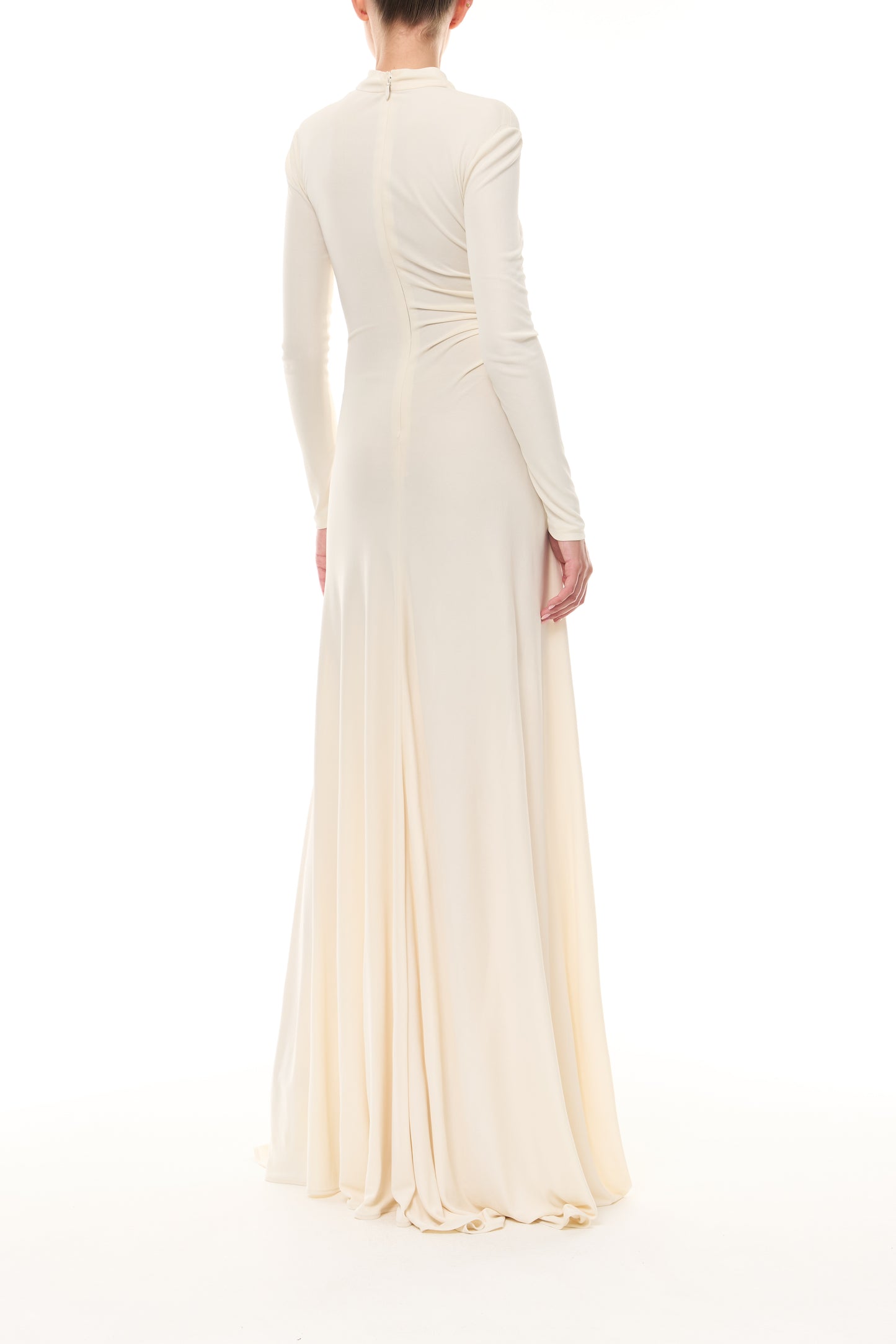 Monique Lhuillier Spring 2026 Ivory crepe jersey high neck long sleeved draped gown with slit and gold ball piercing - back.