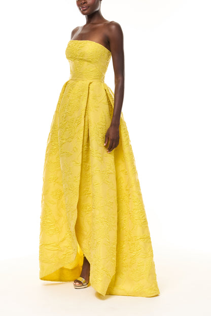 Monique Lhuillier Spring 2026- wearing Buttercup Botanical Matelassé strapless draped gown with slit - side.