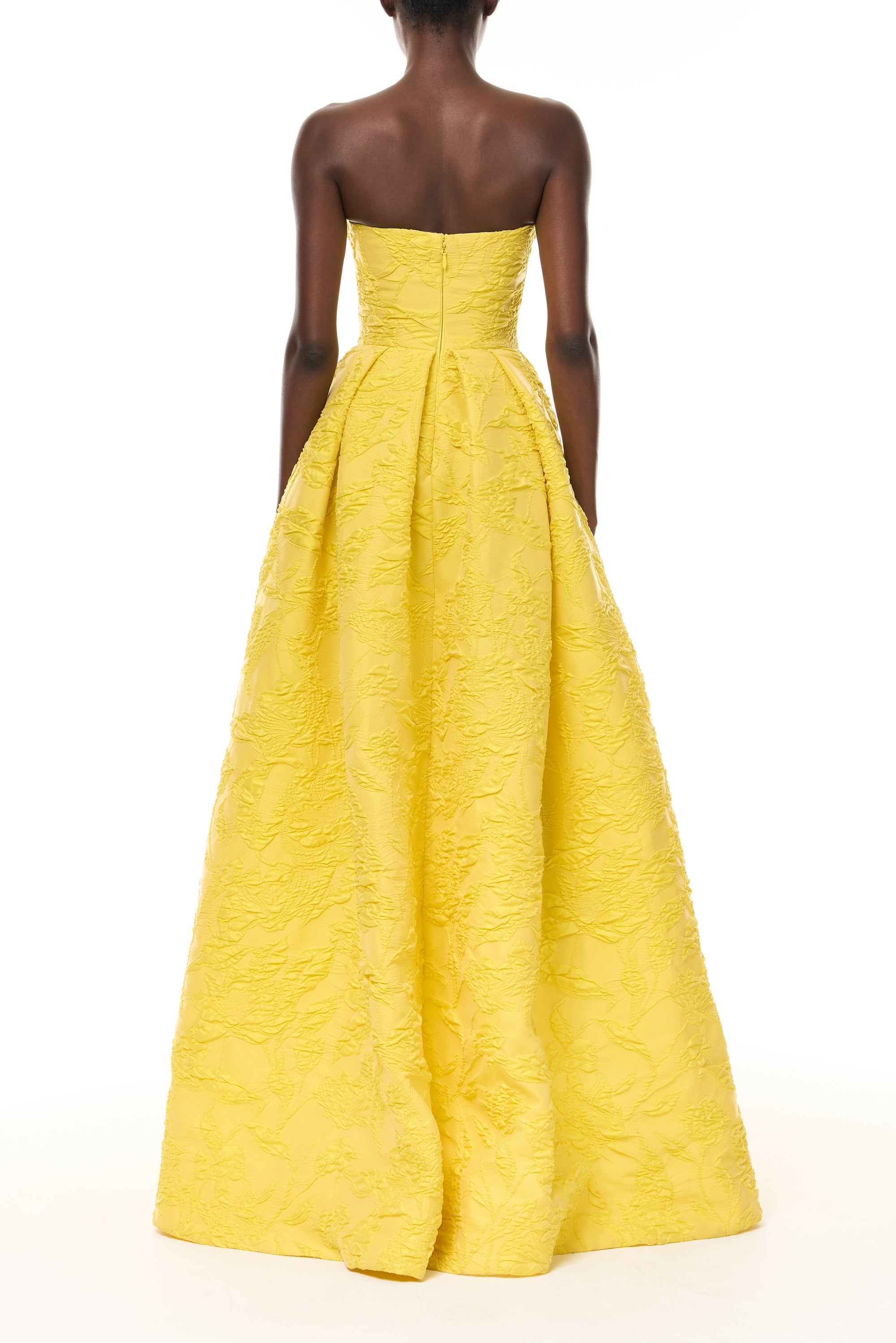 Monique Lhuillier Spring 2026- wearing Buttercup Botanical Matelassé strapless draped gown with slit - back.