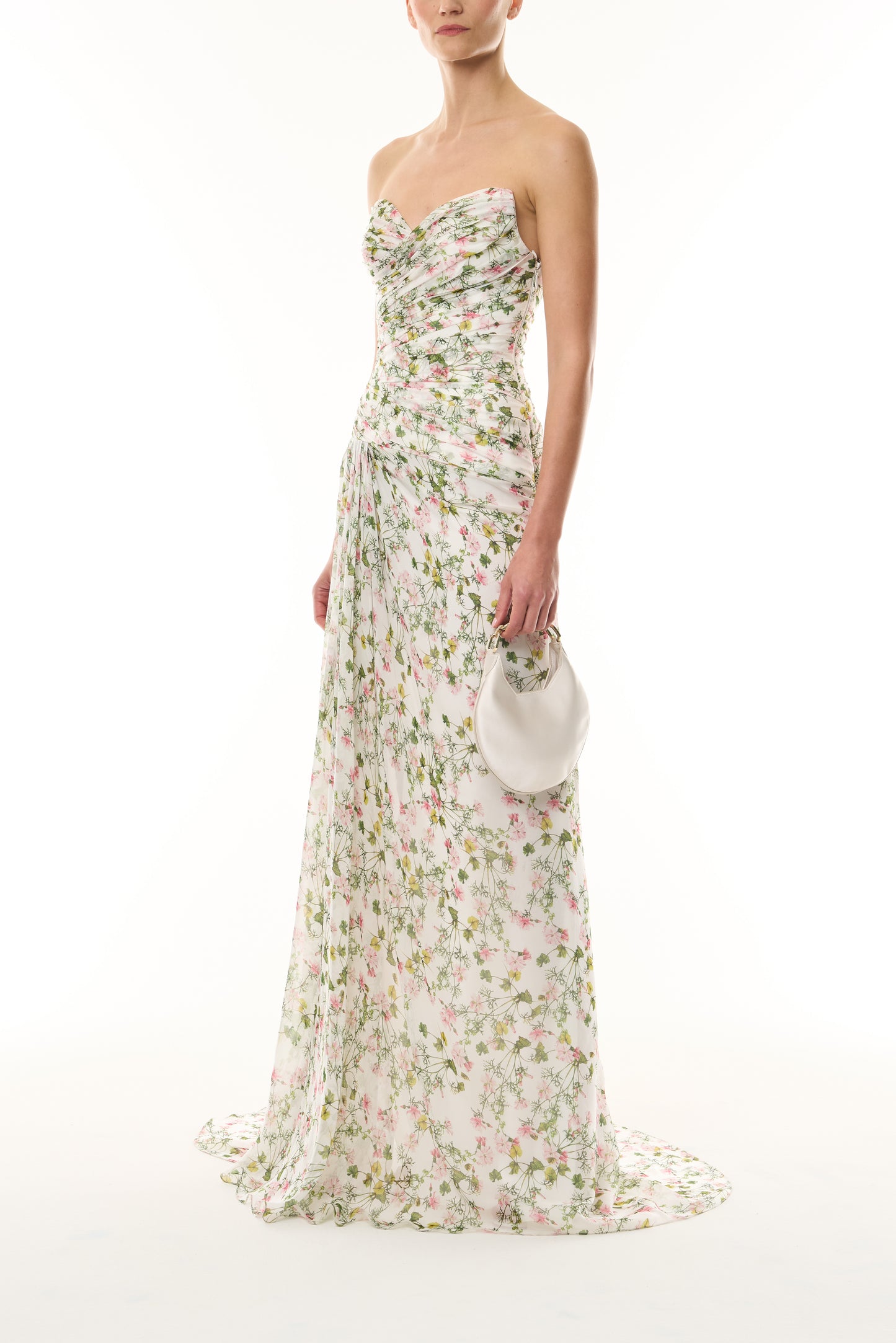 Monique Lhuillier Fall 2026 Silk White/Multi Ivy Bloom Printed Silk Chiffon Strapless asymmetric draped bodice gown - side with Pearl Demi Evening Bag.