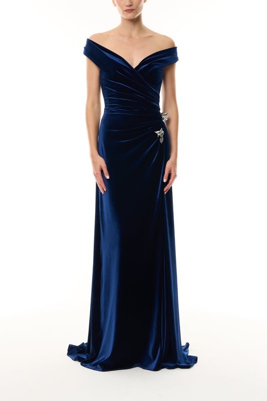Monique Lhuillier Fall 2026 Navy off-the-shoulder stretch velour draped floor length gown with slit and silver floral embellishment - front. 