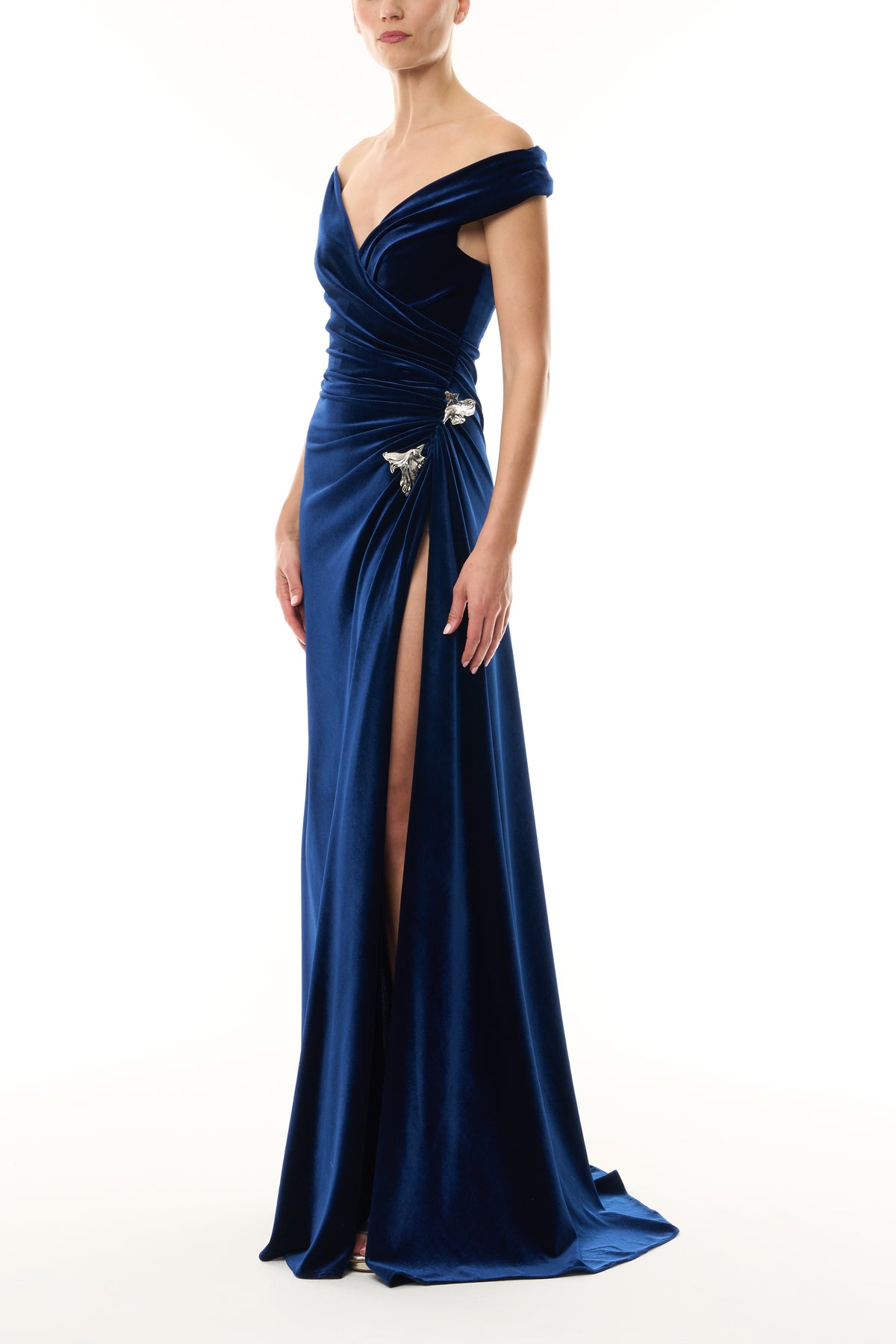 Monique Lhuillier Fall 2026 Navy off-the-shoulder stretch velour draped floor length gown with slit and silver floral embellishment - side.