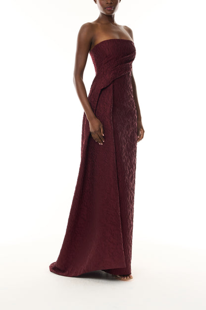 Monique Lhuillier Fall 2026 Rhubarb Jacquard strapless draped column gown with side train - side.