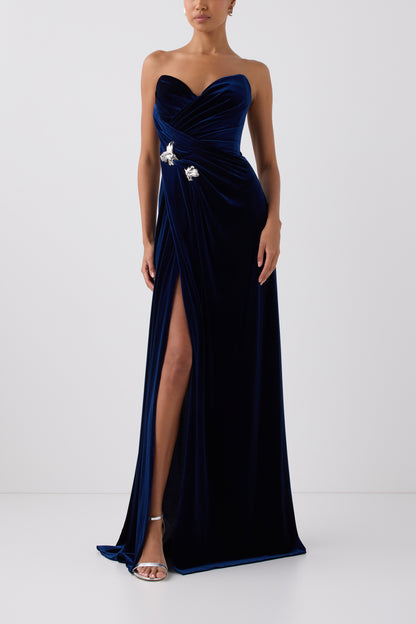 Monique Lhuillier Fall 2026 Navy stretch velour draped gown with slit and silver floral embellishment - front. 