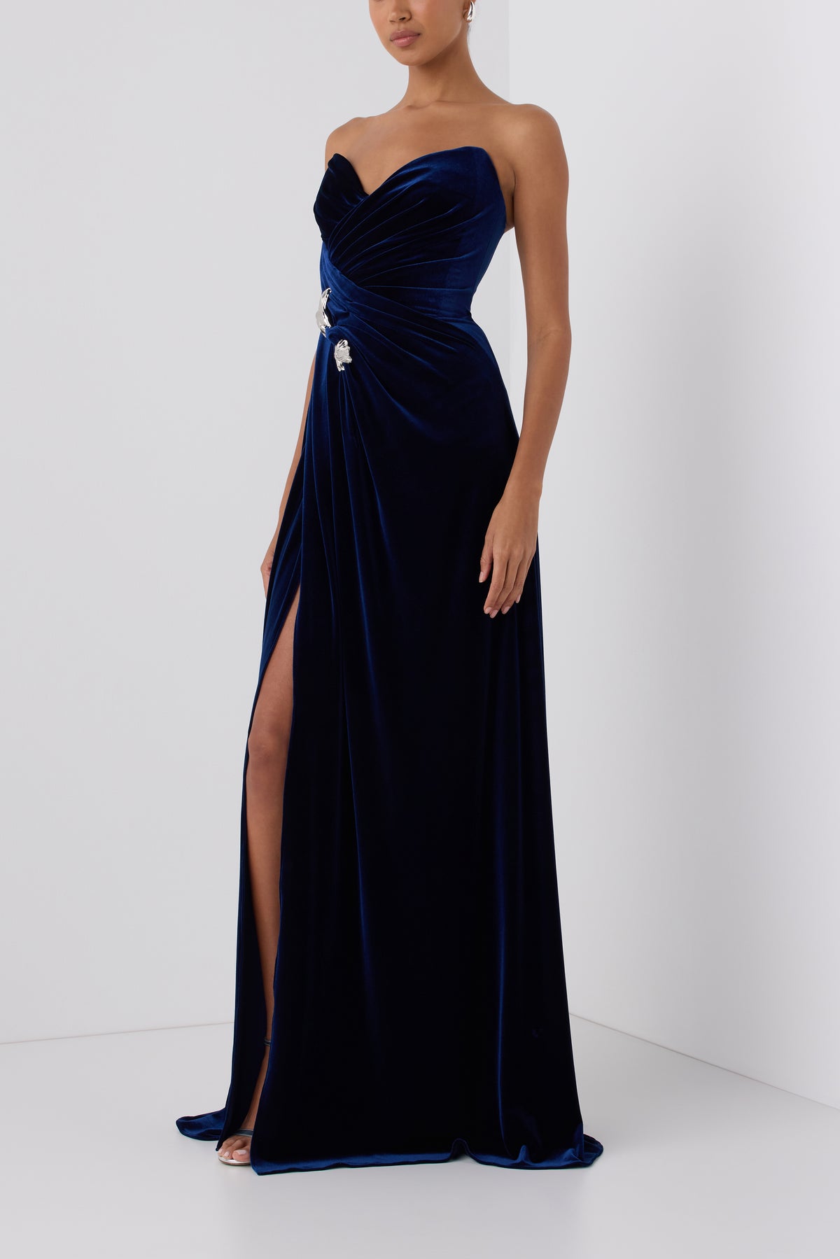 Monique Lhuillier Fall 2026 Navy stretch velour draped gown with slit and silver floral embellishment -side. 