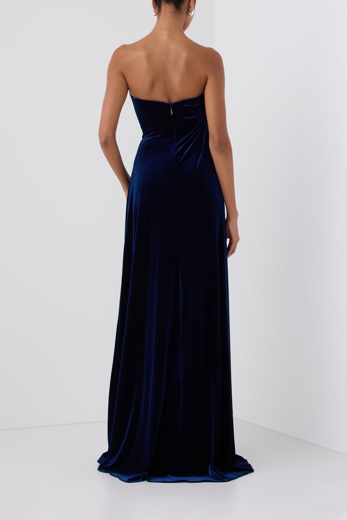 Monique Lhuillier Fall 2026 Navy stretch velour draped gown with slit and silver floral embellishment - back. 