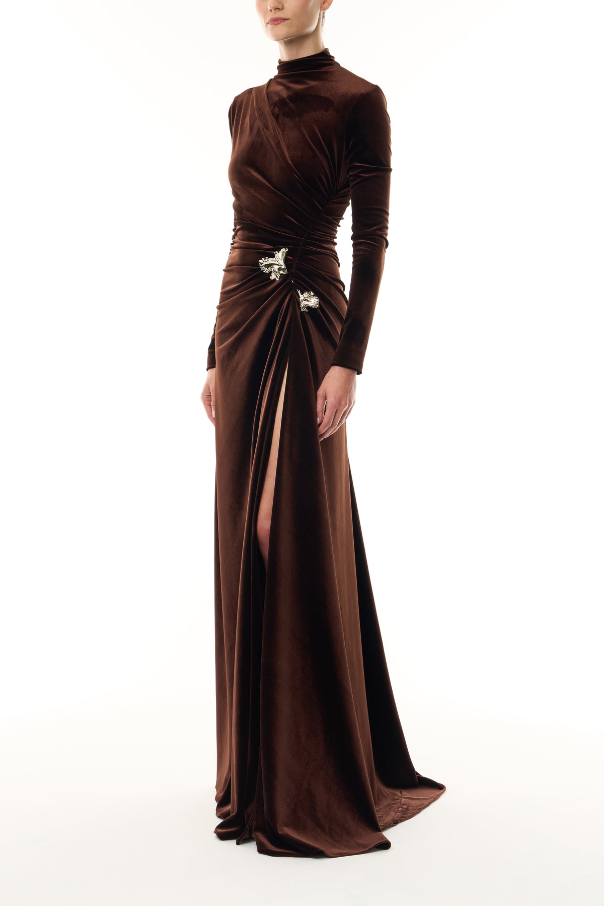 Monique Lhuillier Fall 2026 Café brown stretch velour high neck long sleeve gown with slit and gold floral embellishment -side.