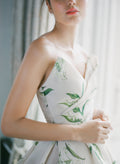 Woman in window wearing Monique Lhuillier Fall 2021 strapless ivory and green lily of the valley printed Sweetness ballgown
