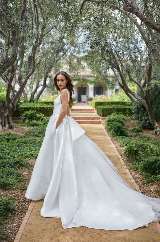 Model in white satin a-line gown with long train