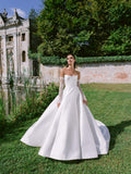 Woman wearing Monique Lhuillier Fall 2024 white mikado strapless scoop neck Passion ballgown with detachable opera-length lace sleeves