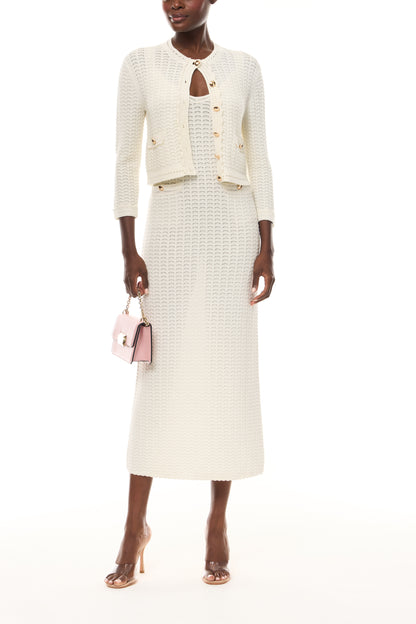 Monique Lhuillier Spring 2026 Ivory Cotton Viscose Knit Lace stitch cardigan with gold buttons with coordinating dress and blush Rhea Mini Shoulder Bag - front.