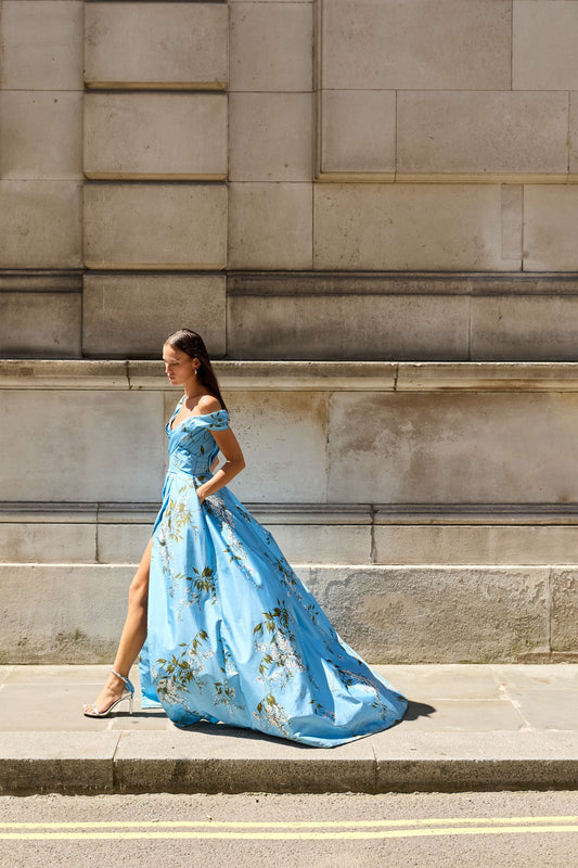 Monique Lhuillier Fall 2026 Blue wisteria printed taffeta asymmetric off-the-shoulder draped ballgown with slit- lookbook. 