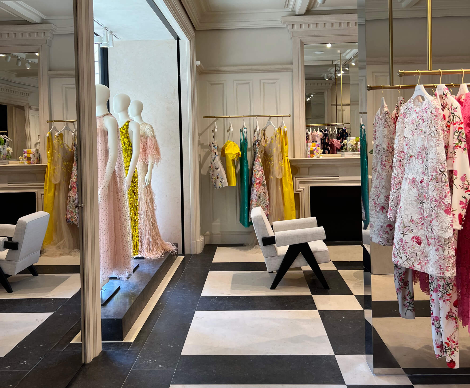 Monique Lhuillier London Flagship store showing ready to wear on racks and mannequins with black and white checked floors.