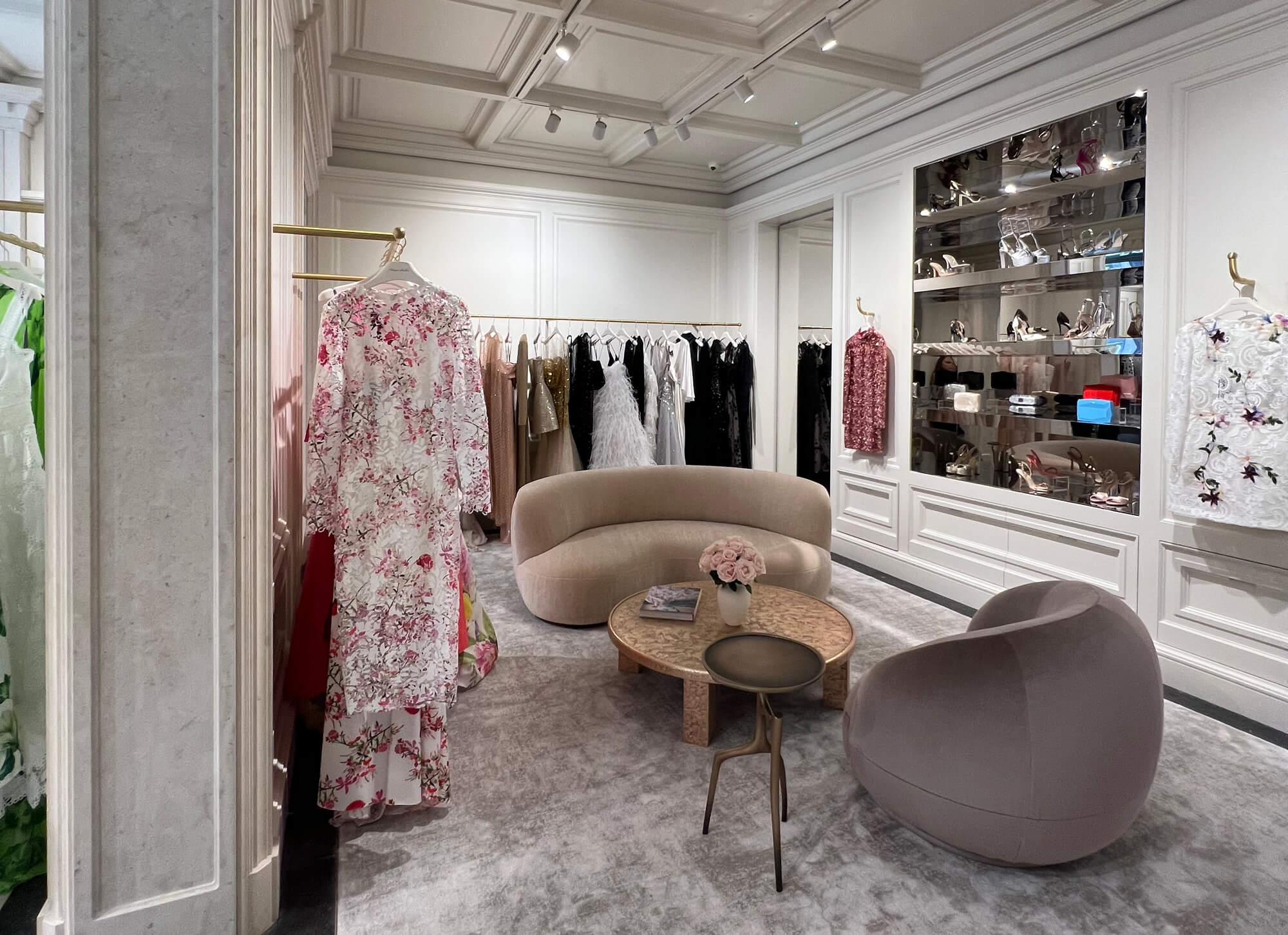 Monique Lhuillier London Flagship store showing ready to wear on racks with shoes and handbags on display.