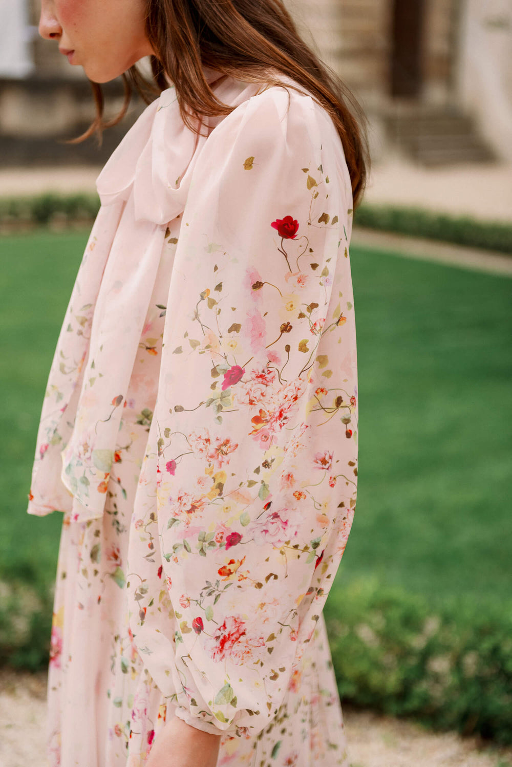 Monique Lhuillier Spring 2024 long sleeve gown with attached necktie and gathered waist in buff floral printed chiffon.