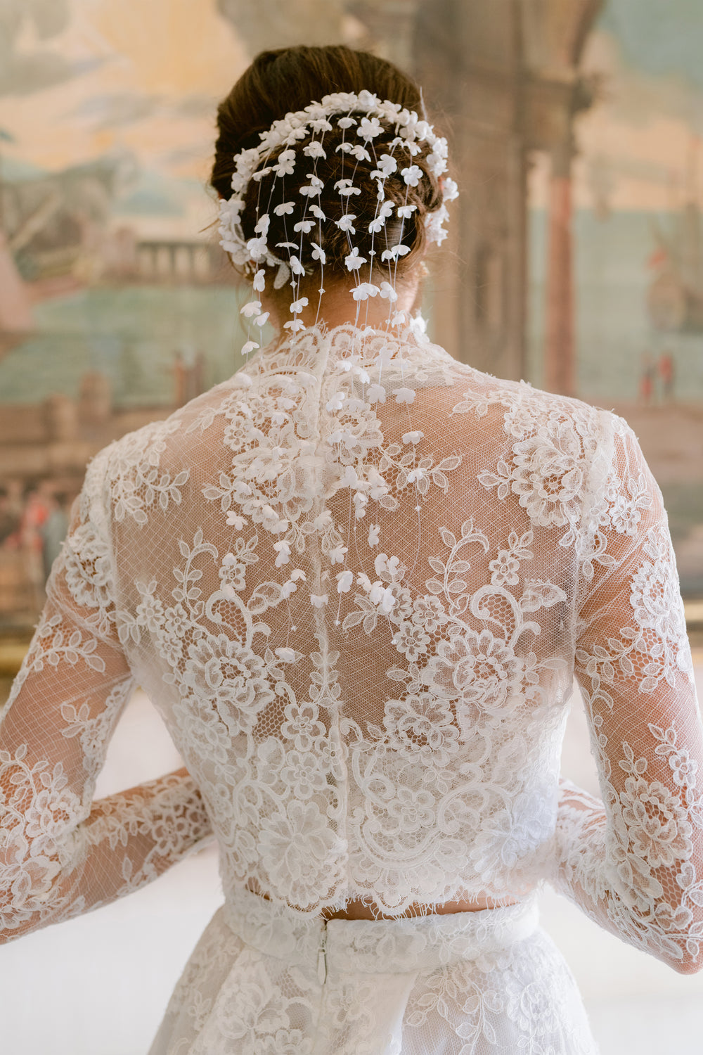 Th back of the Melrose long sleeve bridal jacket in silk white lace - shown on model.