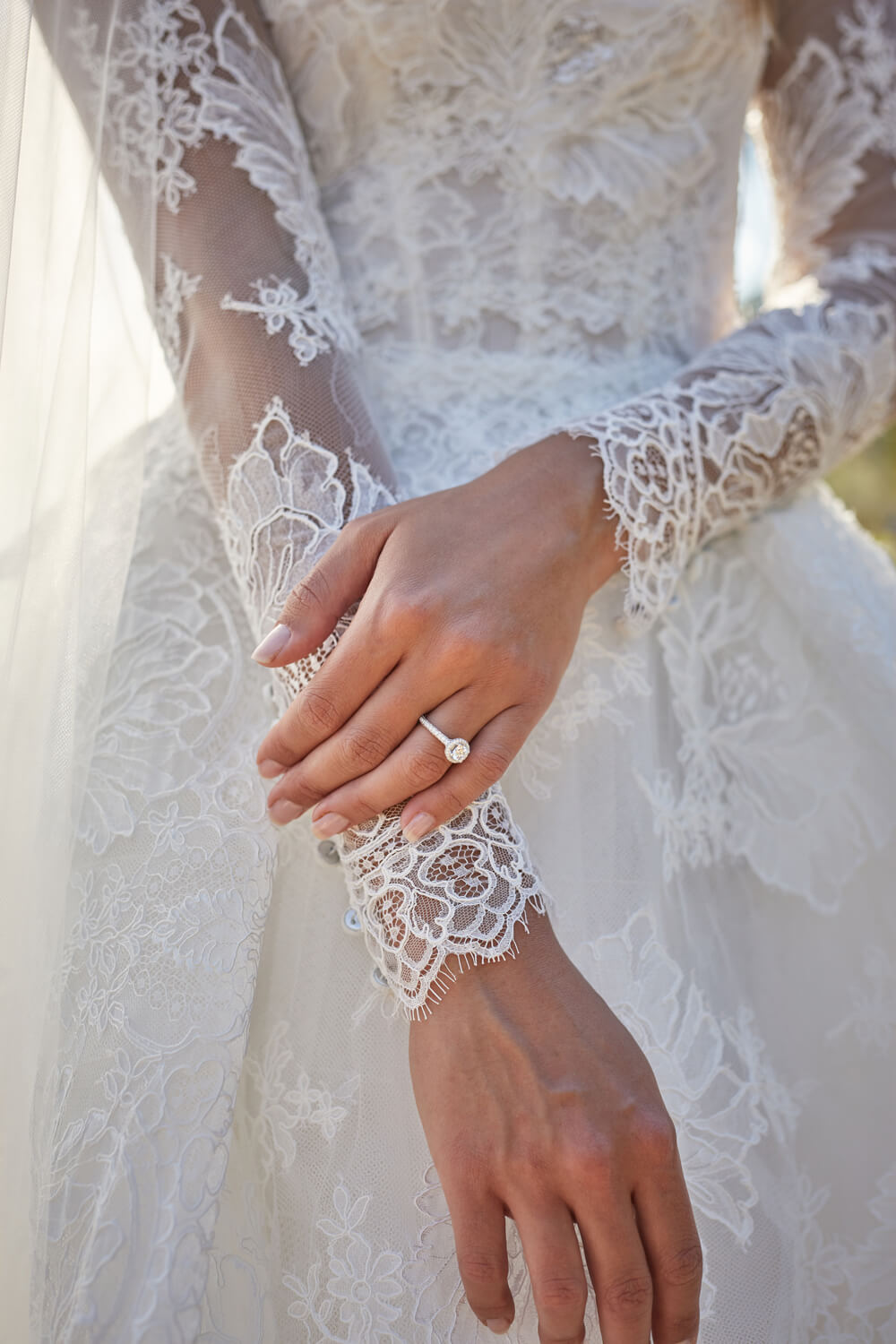 Model's hands with engagement ring in Magnificent lace long sleeve jacket and Magnificent lace a-line gown