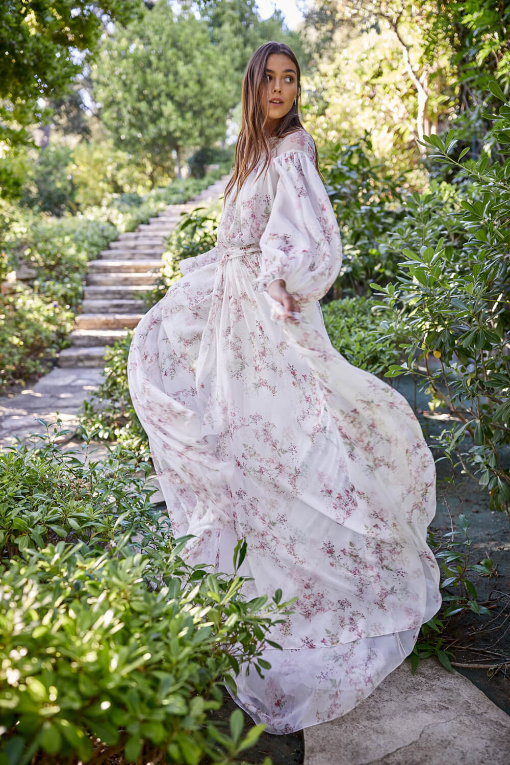 Woman wearing white and pink floral print long sleeve sheath Monique Lhuillier Spring 2021 Cressida gown