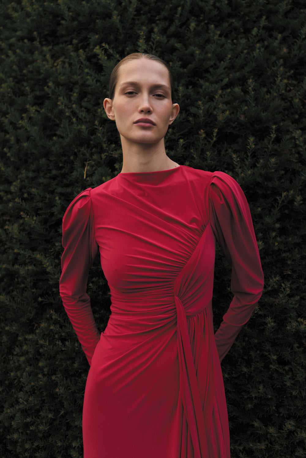 Monique Lhuillier Spring 2024 scarlet red matte jersey long sleeve, gown with draped bodice, jewel neckline and high front skirt slit - lookbook one.