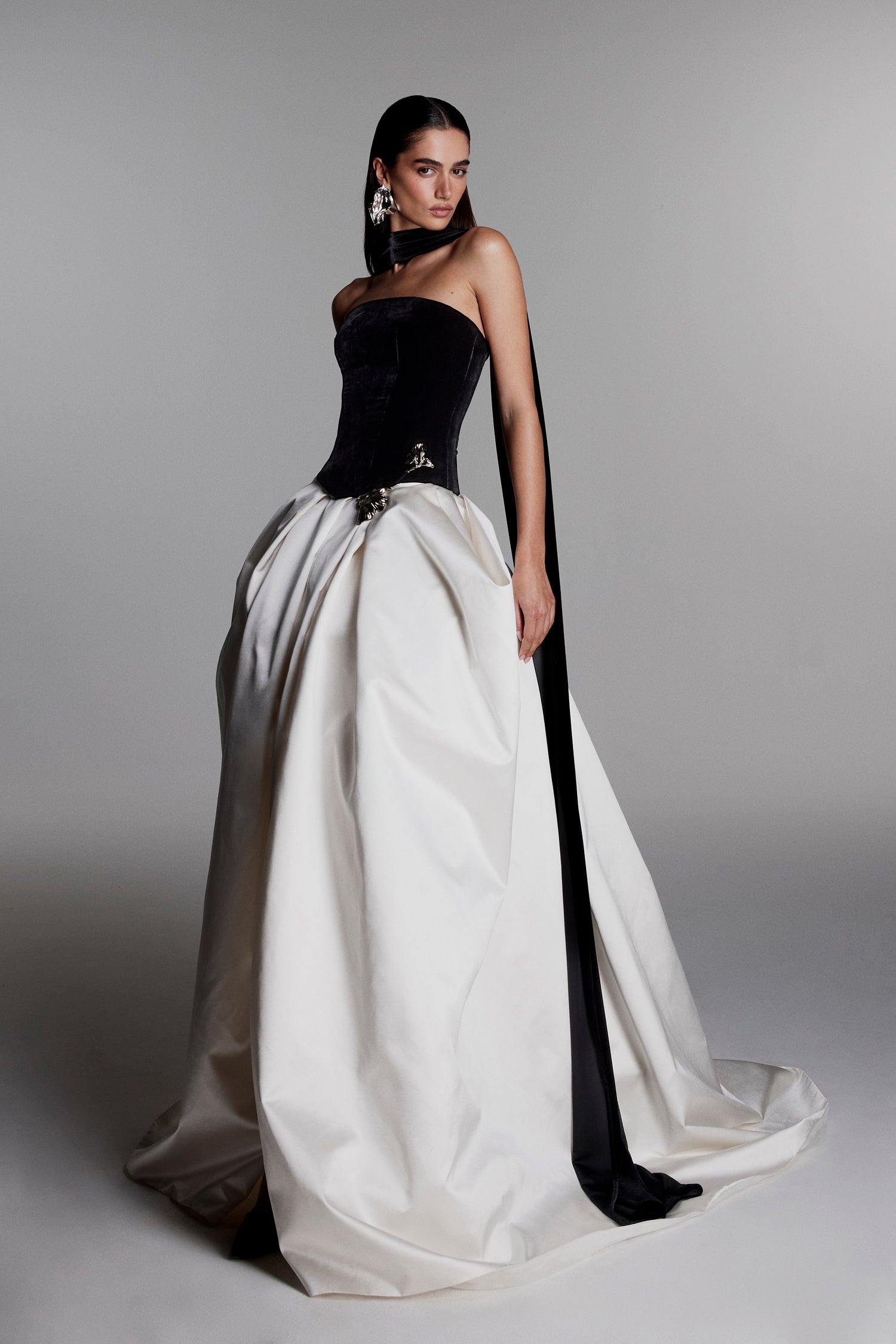 Monique Lhuillier Fall 2026 Noir/Silk White velvet and duchesse satin Strapless
dropped waist ball gown with floral
embellishment and scarf - lookbook.