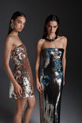 Monique Lhuillier Fall 2026 Rose Gold embroidered sequin strapless mini dress with three dimensional florets; model on right wearing Chrome/Multi embroidered sequin strapless column gown - lookbook.