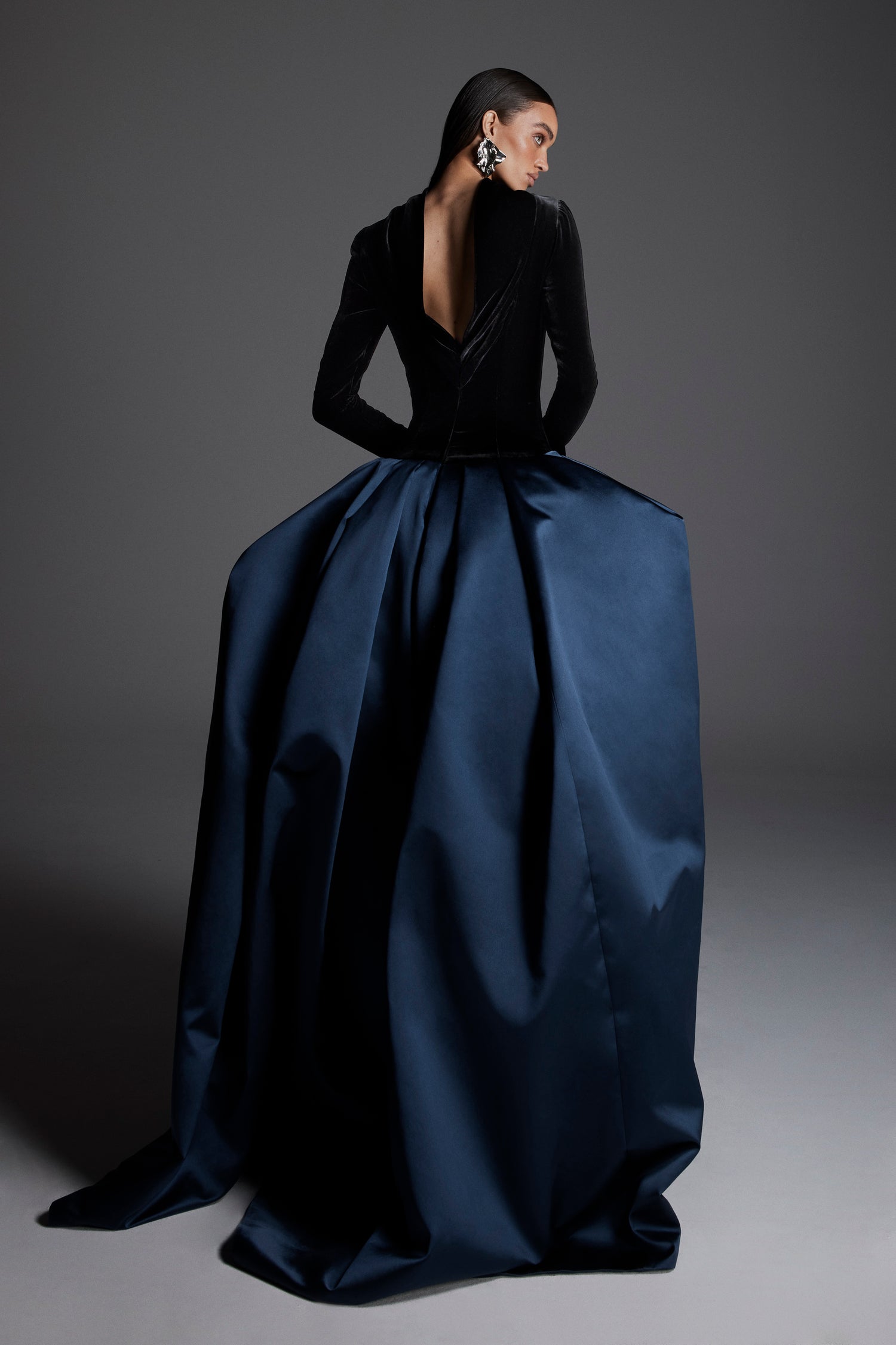 Monique Lhuillier Fall 2026 Noir/Navy velvet and duchesse satin long sleeve dropped waist ballgown with open cowl back - lookbook.