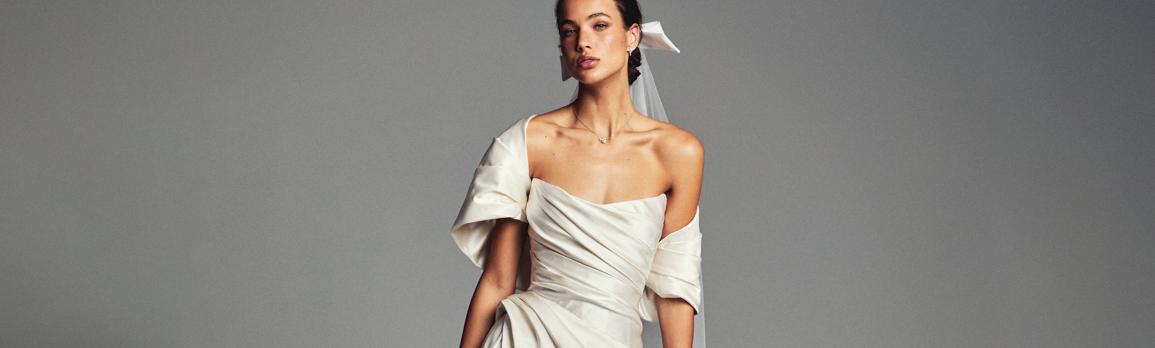 Monique Lhuillier Spring 2027 Bridal strapless draped A-line Campbell gown in ivory silk duchesse satin with asymmetrical draped shrug.