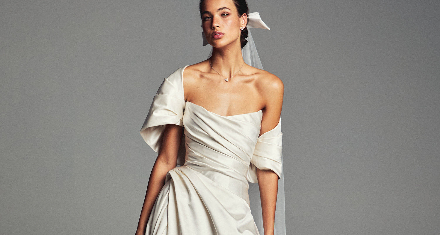 Monique Lhuillier Spring 2027 Bridal strapless draped A-line Campbell gown in ivory silk duchesse satin with asymmetrical draped shrug.