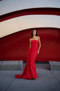 Monique Lhuillier Spring 2026 Poppy Linear Rose Jacquard Strapless Strapless draped column gown with train - model standing on sidewalk.
