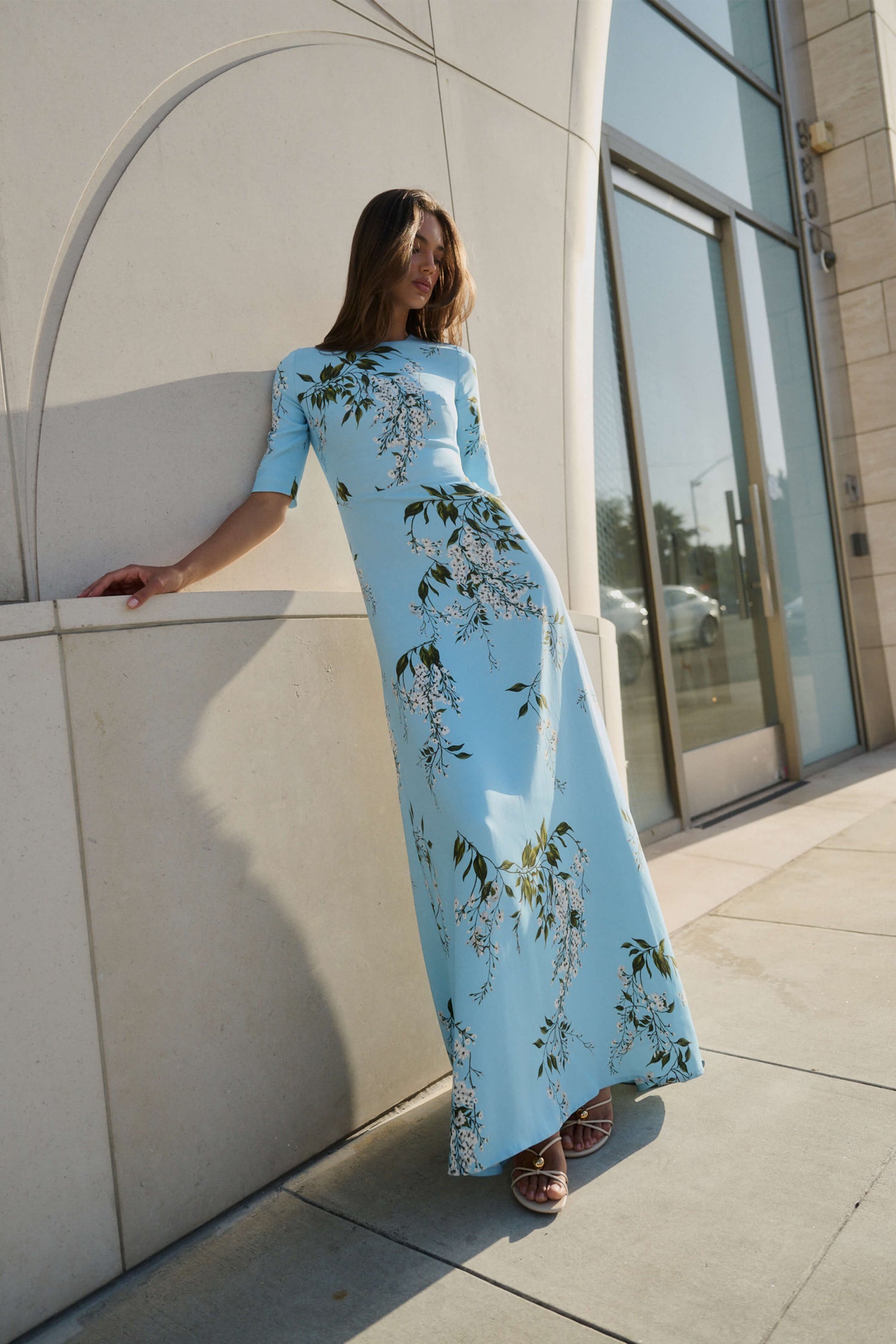 Monique Lhuillier Fall 2026 Horizon Blue Multi Wisteria Printed Crepe Short sleeve gown - model on sidewalk outside.