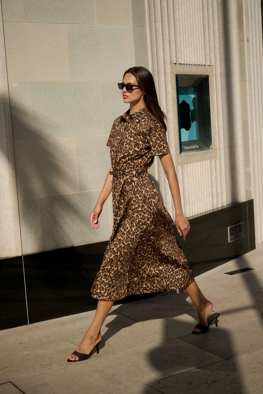 Monique Lhuillier Spring 2026 Leopard Printed Cotton Poplin short sleeve shirt
dress with belt - model walking outside on sidewalk. 