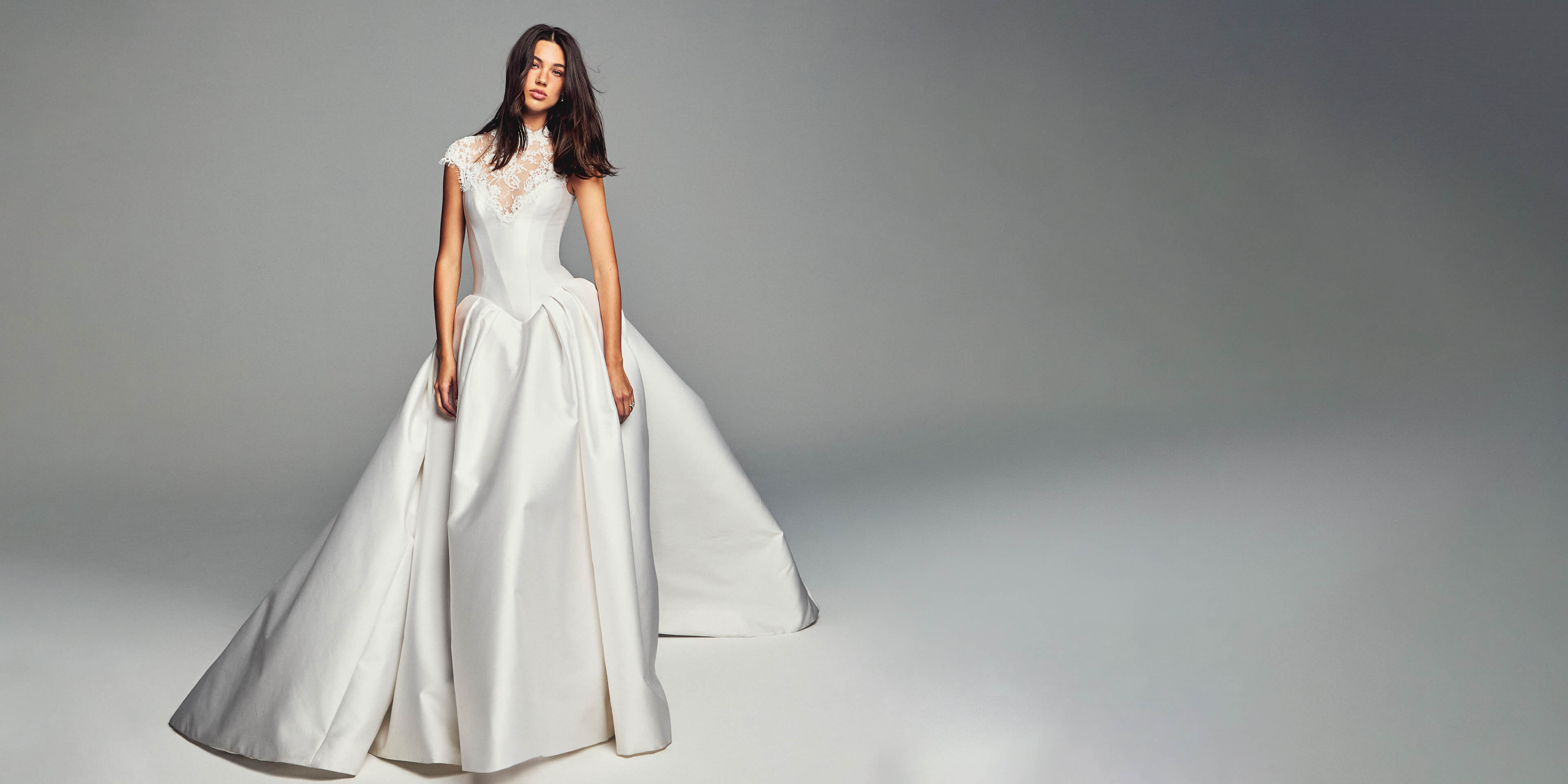 Monique Lhuillier Spring 2027 Bridal Corseted basque waist Spencer ball gown with high neck cap sleeve neckline in silk white Mikado and re-embroidered lace.