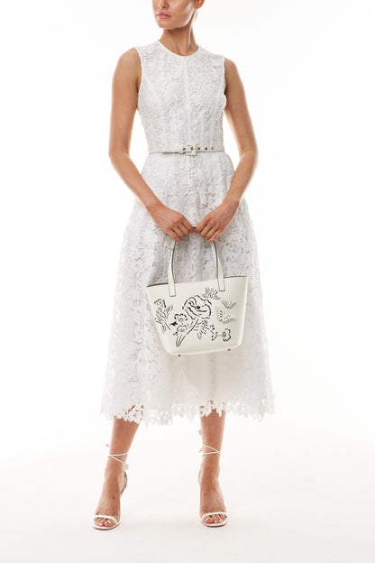 Monique Lhuillier Fall 2025 Silk White orchid lace sleeveless dress with belt - front with Ivory Colette tote. 