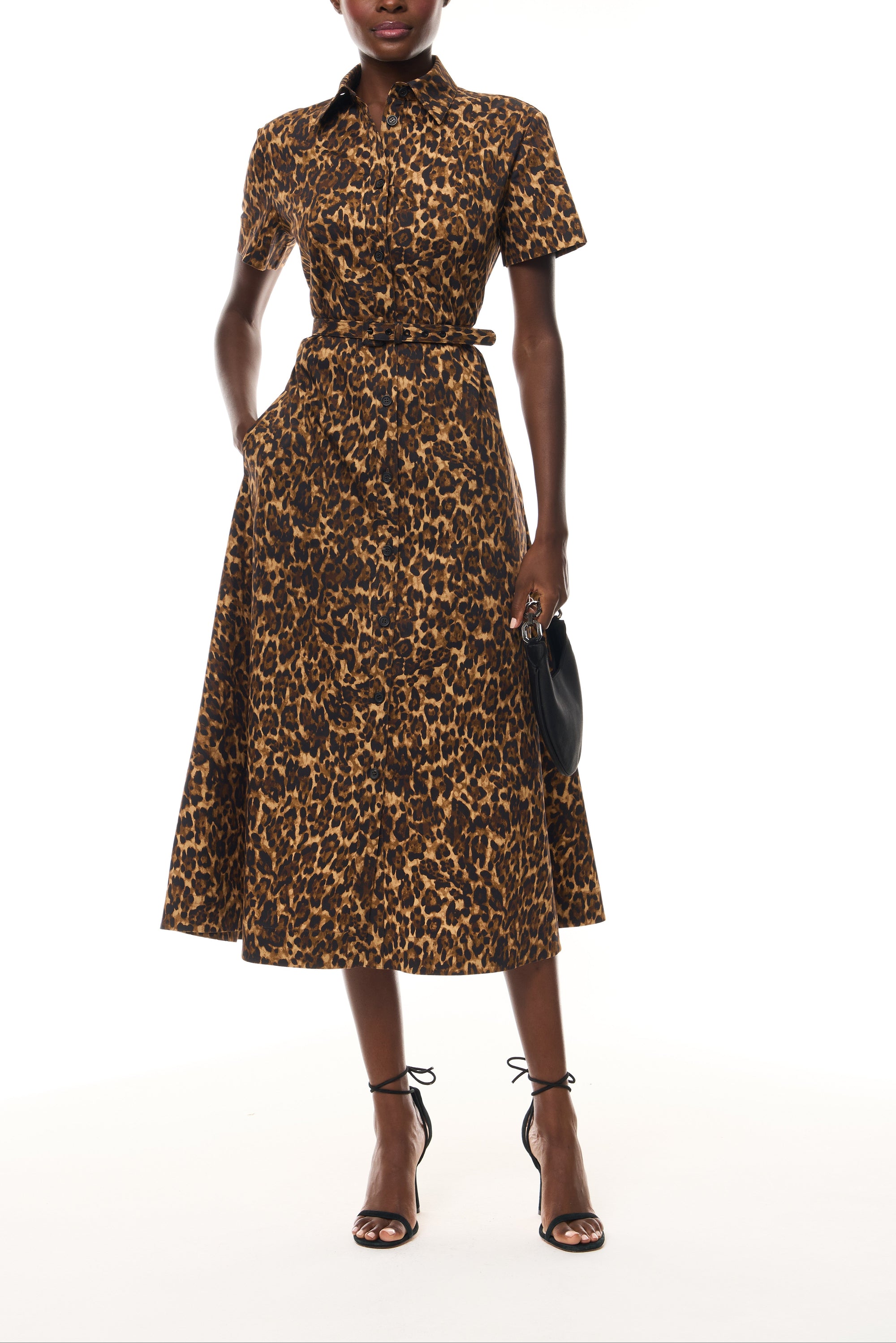 Monique Lhuillier Spring 2026 Leopard Printed Cotton Poplin short sleeve shirt
dress with belt - front with Noir Demi evening bag.