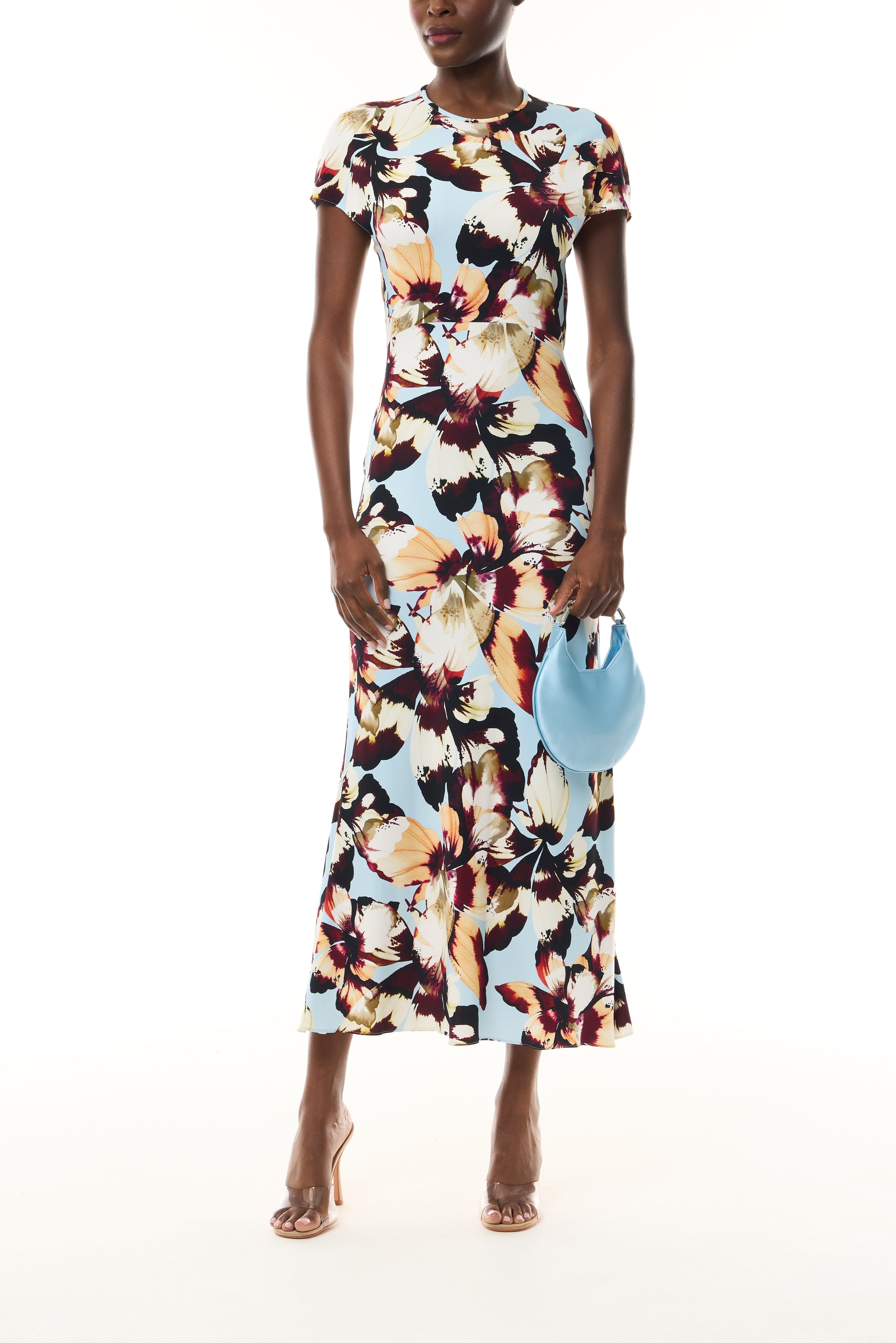 Monique Lhuillier Fall 2026 Breeze/Multi Amber Lily Stretch Crepe Short Sleeve Amber Lily Day Dress - front with Pale Blue Demi Evening bag.
