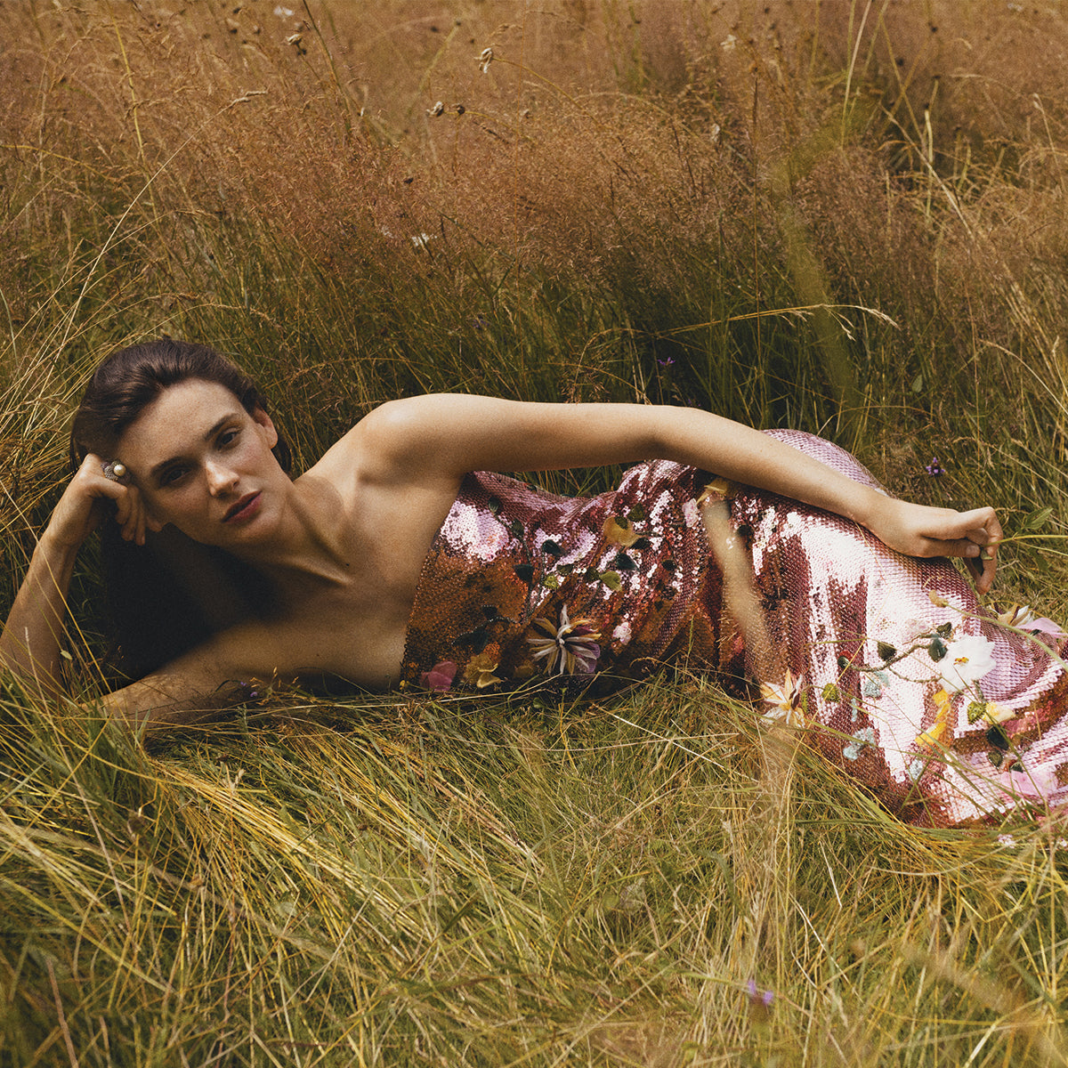 Monique Lhuillier Spring 2024 Cerise/multi Strapless embroidered sequin gown - lookbook photo of model laying in grassy field 